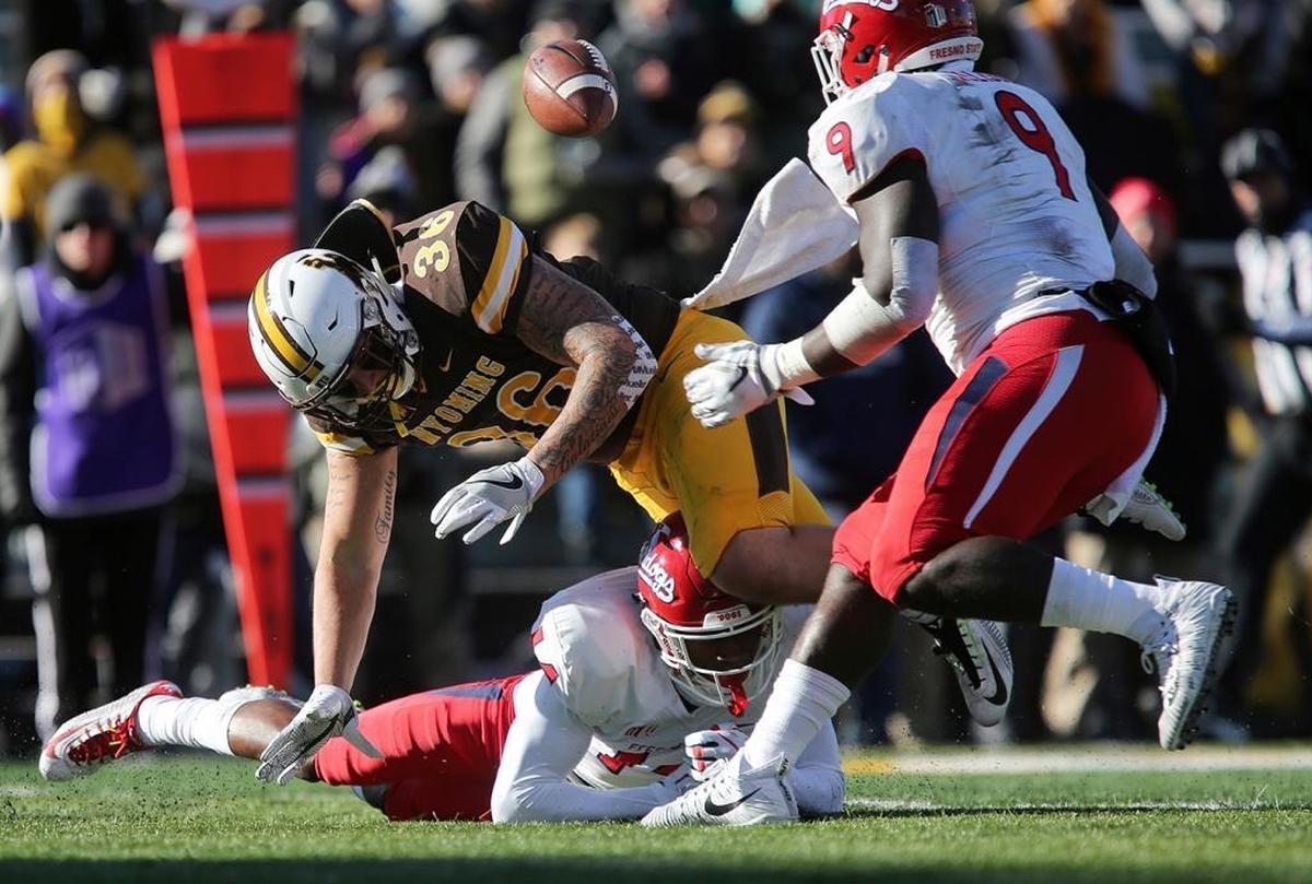 Wyoming fullback Drew Van Maanen fumbles while being tripped up by Fresno State defensive back Jaron Bryant (14) during the Bulldogs’ 13-7 victory at War Memorial Stadium on Saturday, Nov. 18, 2017, in Laramie, Wyo. Fresno State, 1-11 last season, clinched a West Division title and spot in the Mountain West Conference championship game with the victory.