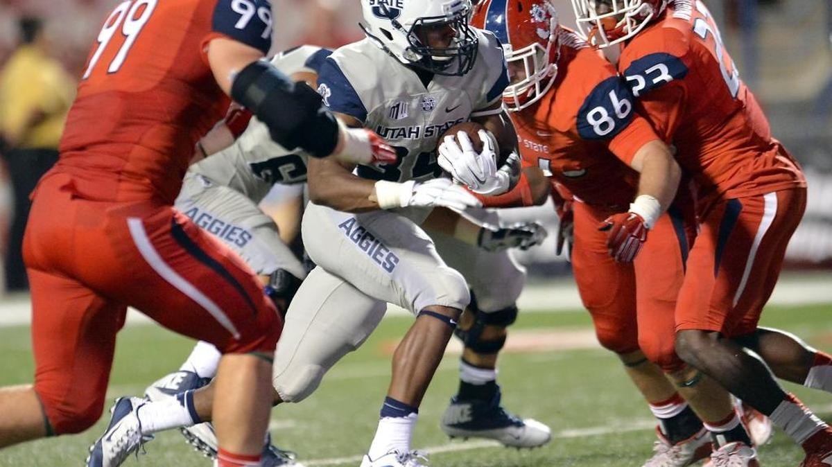 Fresno State’s Nick Kristofors (99), Kyle Hendrickson (86) and Alan Wright (23) try to close off a run by Utah State’s Justen Hervey in an October game. Kristofors was one of the pleasant surprises among the Bulldogs’ late signings heading into last season, playing in all 12 games after transferring from Santa Rosa JC.