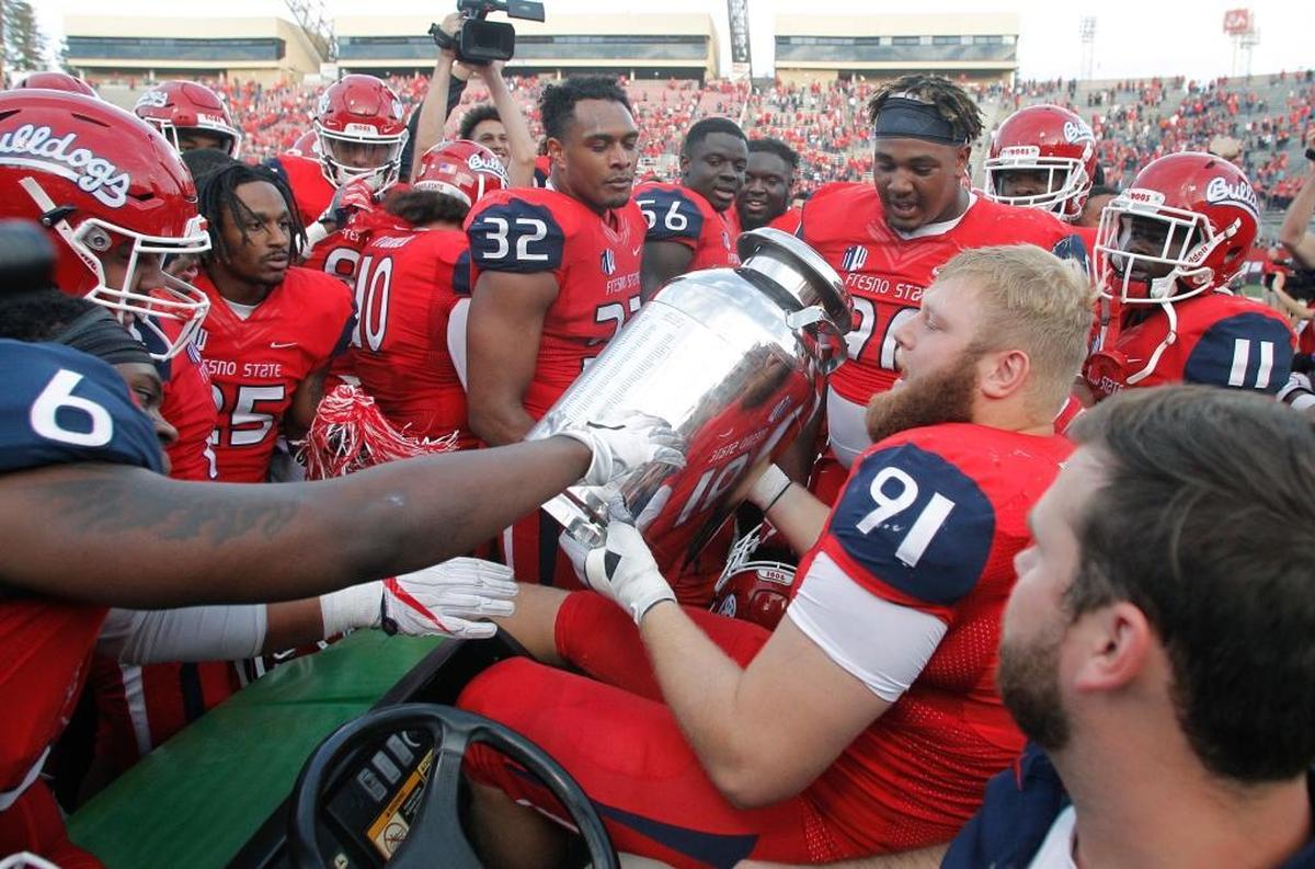 Fresno State defensive tackle Nathan Madsen, who suffered a season-ending knee injury in the Bulldogs;’ 28-17 victory over Boise State, hoists the Milk Can Trophy as teammate surround him, Saturday, Nov. 25, 2017, in Fresno. Madsen will make the trip to Boise for the Mountain West Conference championship game.