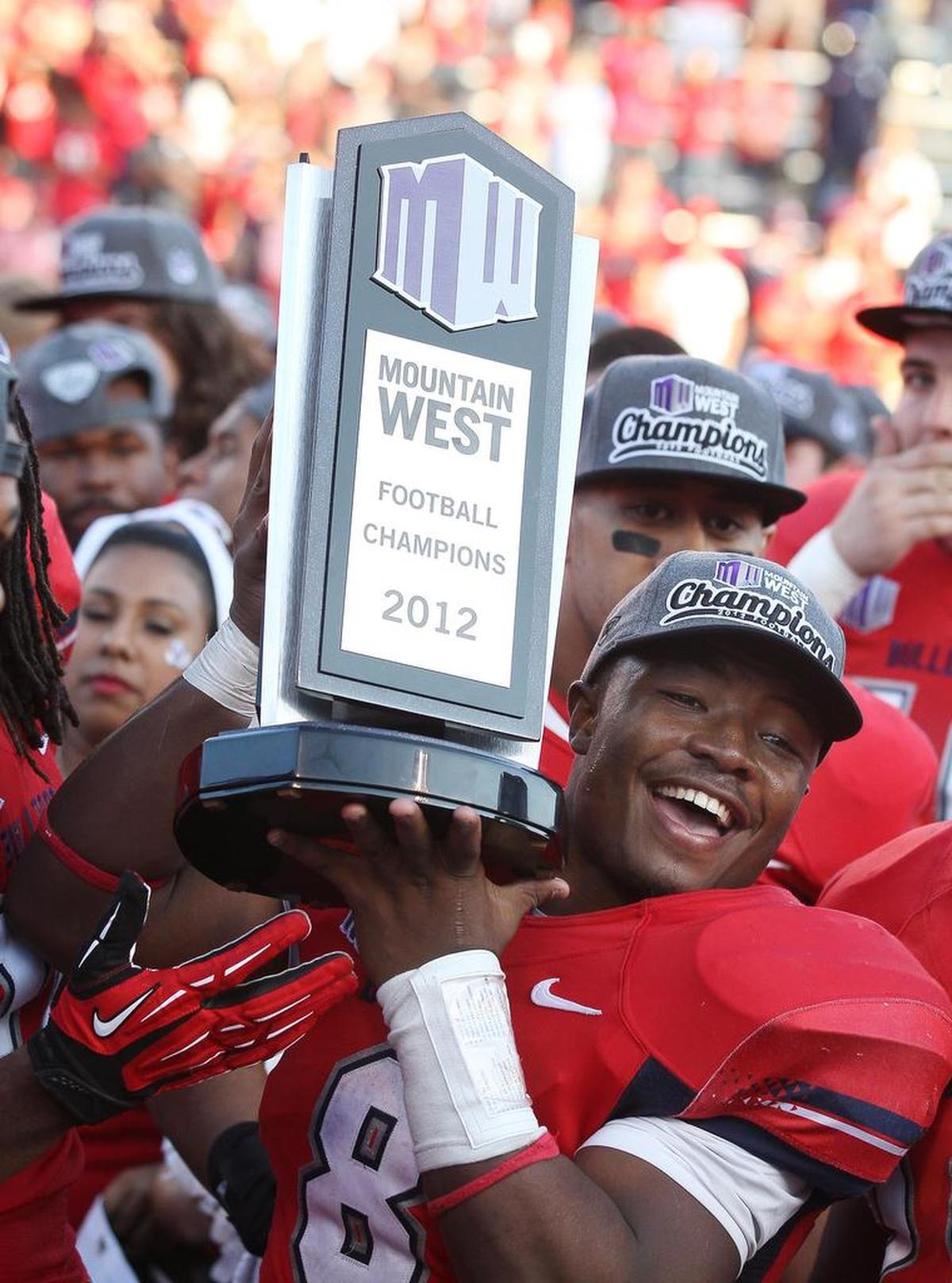 Fresno State’s Robbie Rouse hold up the Mountain West Conference football championship trophy after the Bulldogs beat Air Force at Bulldog Stadium ini 2012.