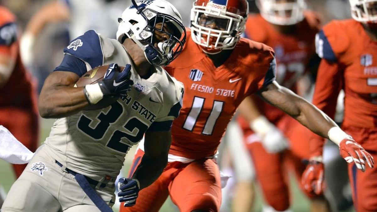 
Utah State’s Devante Mays carries for one of his three touchdowns, eluding Fresno State’s DeShawn Potts, in Saturday night’s game at Bulldog Stadium. Mays ran for 92 yards and three touchdowns on nine carries in a 56-14 victory.
