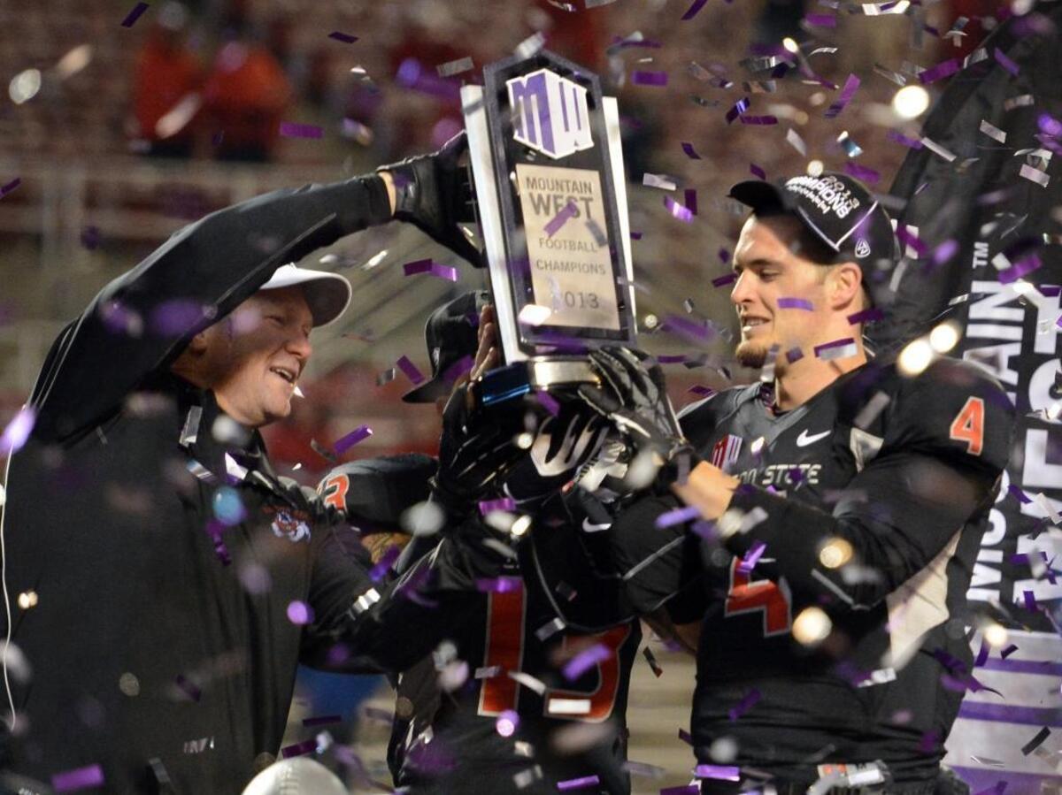 Fresno State coach Tim DeRuyter, left, and quarterback Derek Carr hold up the Mountain West conference championship trophy after the Bulldogs defeated Utah State in the conference championship game at Bulldog Stadium on Saturday, Dec. 7, 2013.
