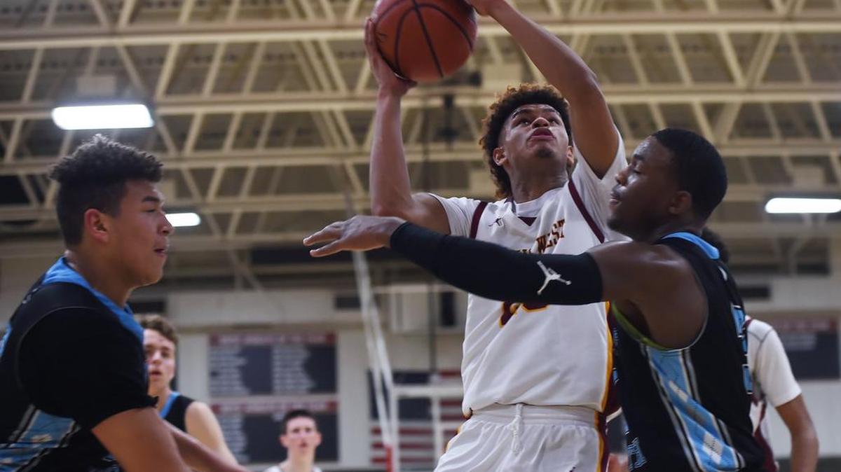 Clovis West’s Dez Walls, center, goes up for a shot with Clovis North’s Terri Miller, left, and Clovis North’s Stephen Perry, right, in the Tri-River Athletic Conference game Monday, Feb. 4, 2019 in Fresno. Clovis West won 75-52.