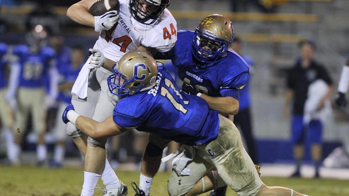 
Central High’s Kyus Eaves tries to break the tackle attempt of Clovis High’s Josh Hokit with Clovis’ Jared Hill to the right. Eaves and the Grizzlies led the No. 1 Cougars 21-12 Thursday in a game suspended by lightning with 6 minutes to play. The game will be completed starting at 10:30 a.m. Saturday at Lamonica Stadium.
