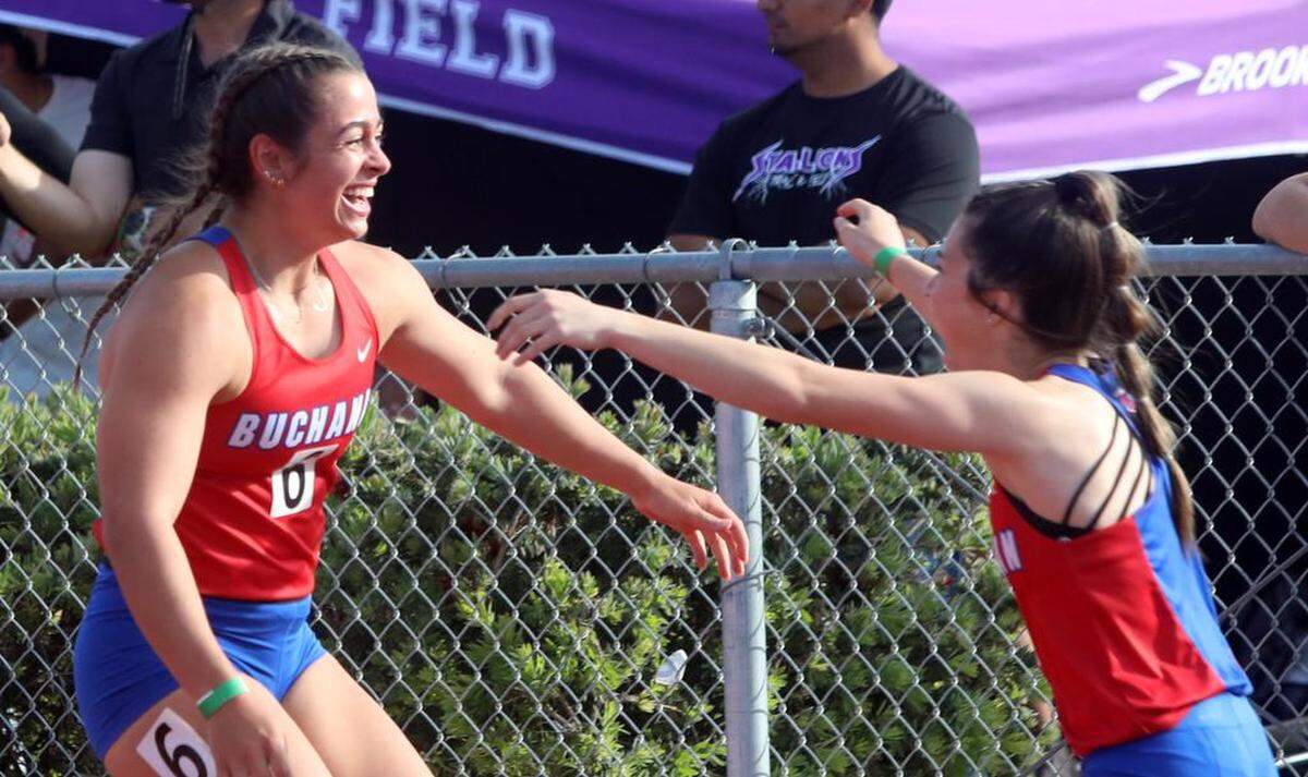 Buchanan High senior Jordan Leveque (left) celebrates her 100-meter win in a personal-best 11.99 with a teammate at the Sanger Metric Classic on April 21, 2023.