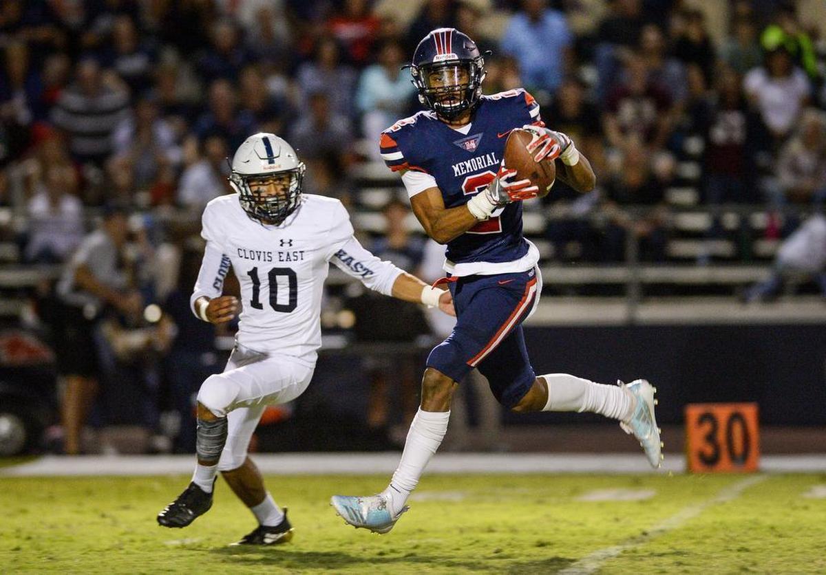 Memorial’s Joshua Kelly, right, catches a pass down the middle while defended by Clovis East’s Justic Cantu in their game at San Joaquin Memorial High School Stadium on Friday, Sept. 14, 2018.