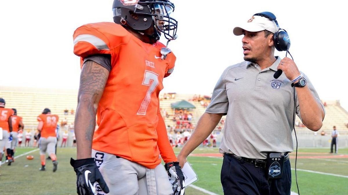 Central High’s Justin Garza, talking with player Savion Simms ahead of a 2014 game, has resigned as the Grizzlies coach.