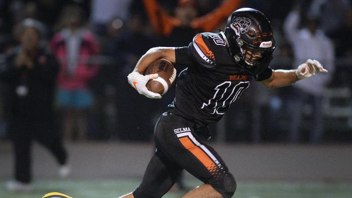 Selma’s Arron Blancas, right, slips away from the grasp of Kingsburg’s Blake Vanbebber before running the ball in for a touchdown during their game at Reedley High School on Friday, Nov. 1, 2019.