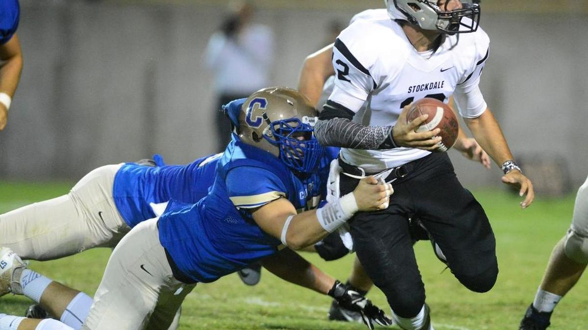 
Clovis’ Tanner Rice, left, pulls down Stockdale quarterback Anthony Onsurez for a sack in their game at Lamonica Stadium on Friday, Sept. 18, 2015.
