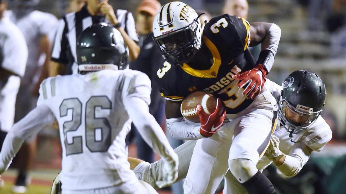Edison’s Velltray Jefferson spins free from Dinuba’s Justin Gonzalez, right, in a September 2019 game.