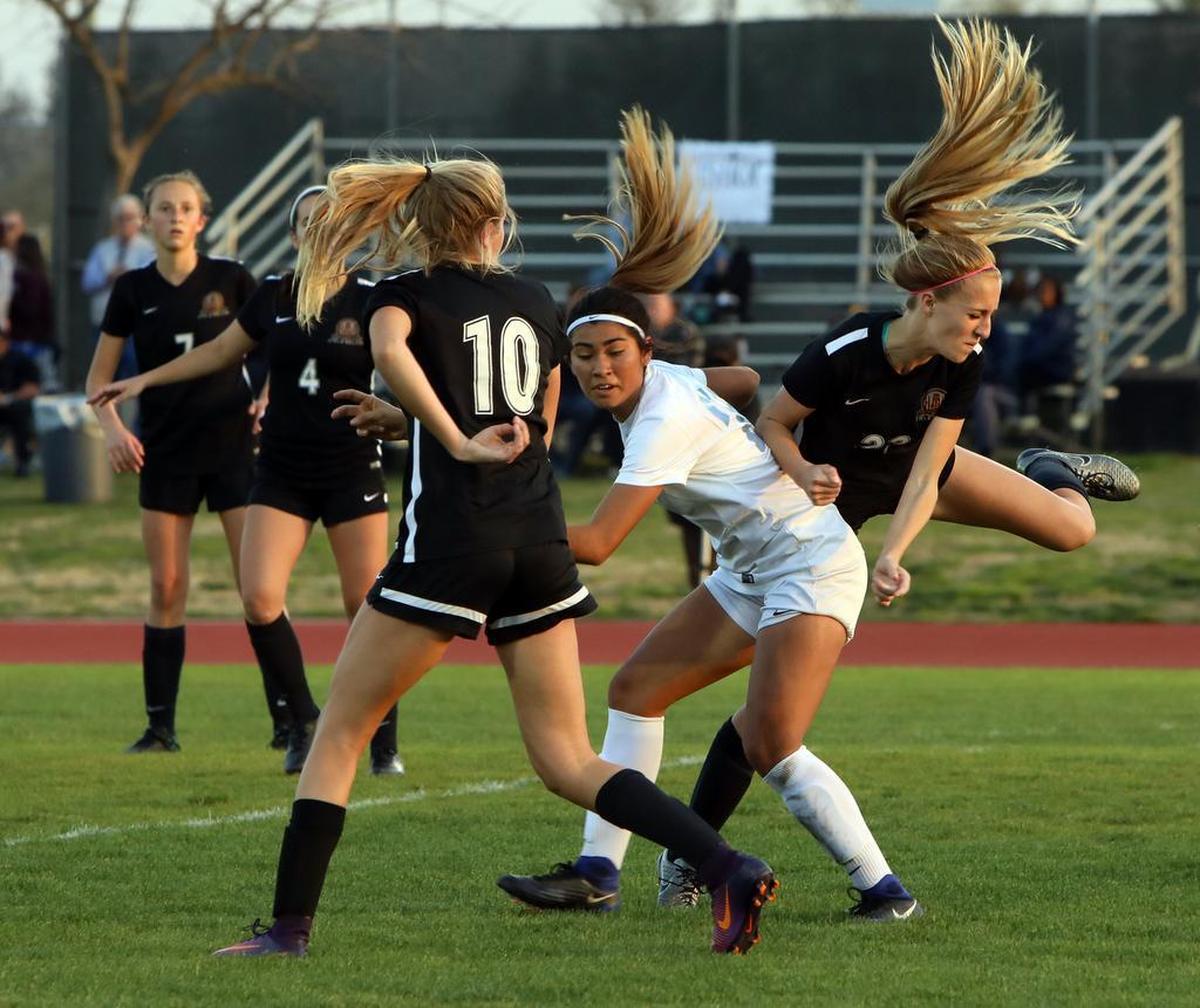 The hair goes flying at Bullard High’s Alyssa Renovato gets defended by Huntington Beach’s Summer Stewart and Alexandra Lotter.