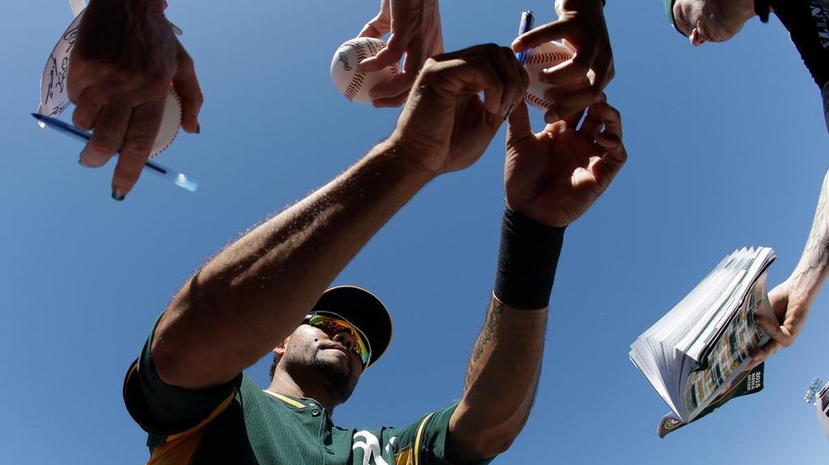 Oakland’s Coco Crisp sings autographs for fans before a spring training game against the Los Angeles Angels, March 7, 2015, in Mesa, Ariz.