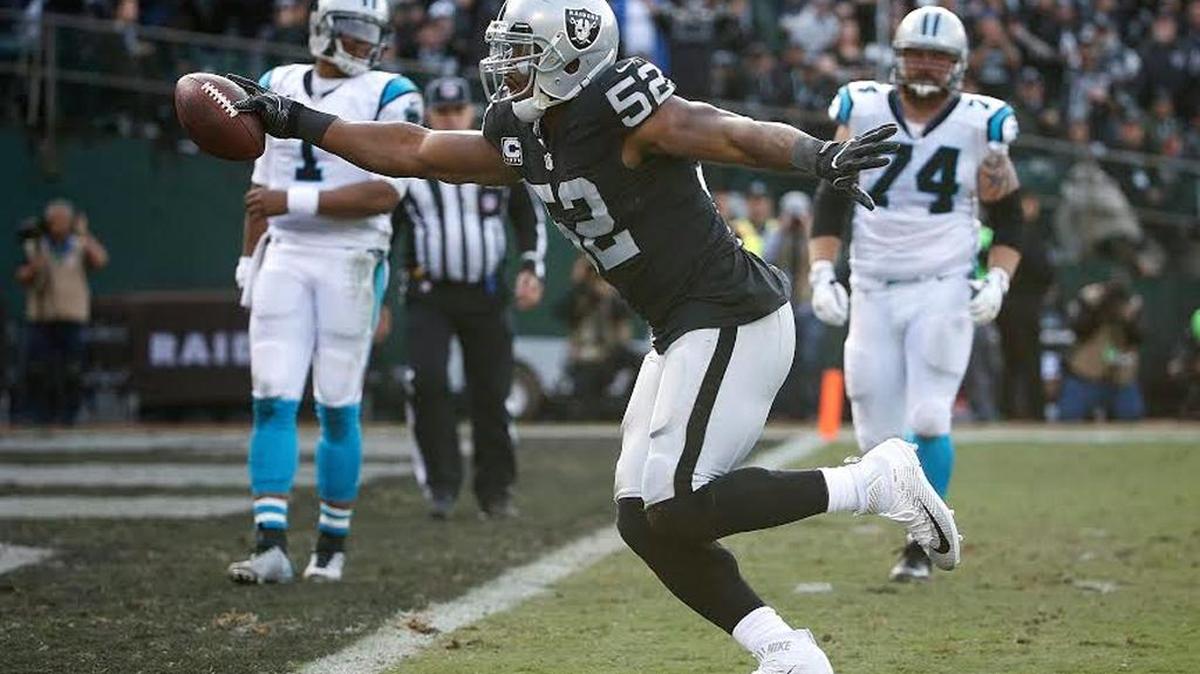 FILE - In this Sunday, Nov. 27, 2016, file photo, Oakland Raiders defensive end Khalil Mack (52) scores a touchdown after intercepting a pass by Carolina Panthers quarterback Cam Newton, left rear, during the first half of an NFL football game in Oakland. The Raiders picked up a fifth-year option on the reigning Defensive Player of the Year.