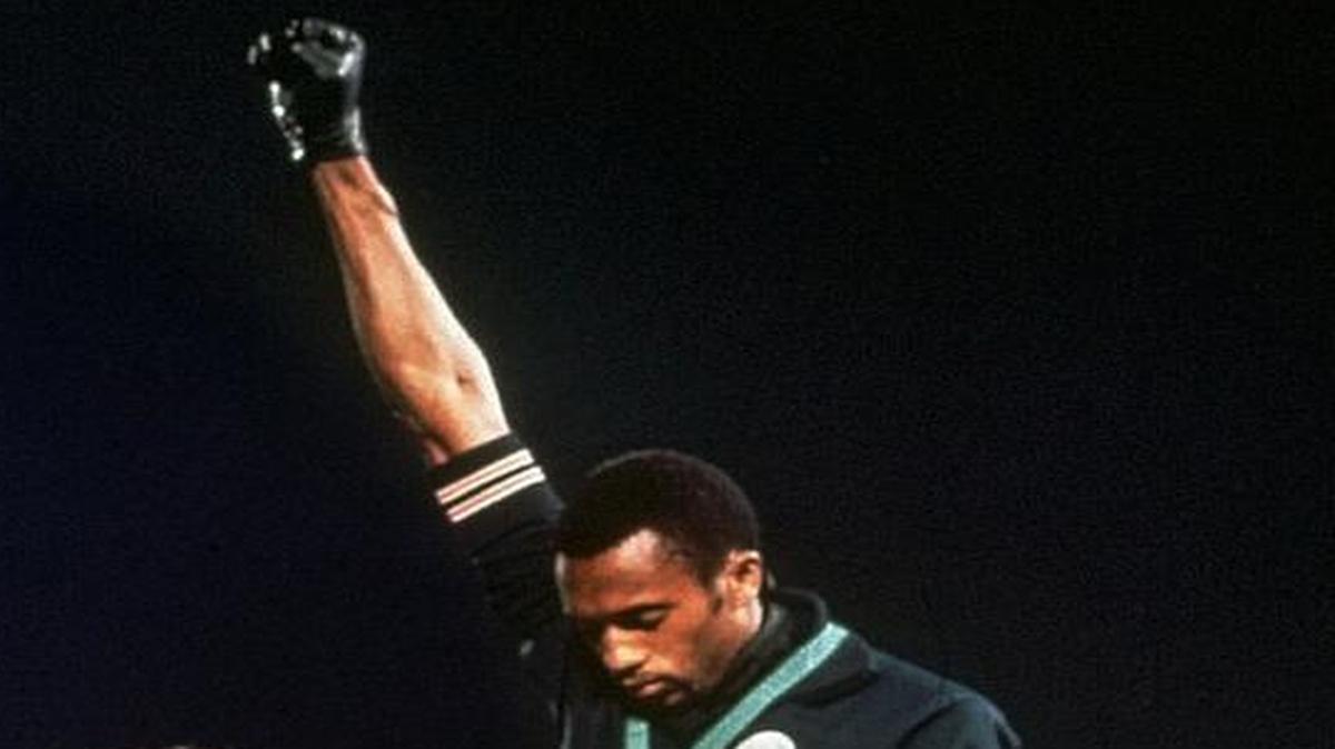 Extending gloved hands skyward in a civil-rights protest, U.S. athletes Tommie Smith, center, and John Carlos stare downward during the playing of “The Star-Spangled Banner” after Smith won gold and Carlos the bronze in the 200 meters at the Summer Olympic Games on Oct. 16, 1968, in Mexico City. Australian silver medalist Peter Norman is at left.