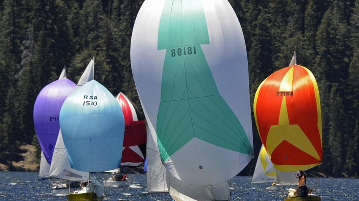 A fleet of sailboats with flying spinnakers approach the finish line at Huntington Lake during the High Sierra Regatta in July 2013. The regatta returns to Huntington Lake this weekend and next weekend after a two-year hiatus due to the drought.
