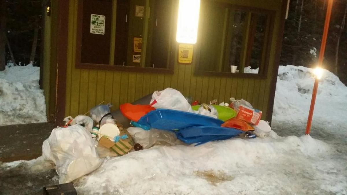 Bags of garbage left by visitors in a pile next to the restroom at the Coyote Snow Park, just beneath a sign reading “Pack it in. Pack it out.”
