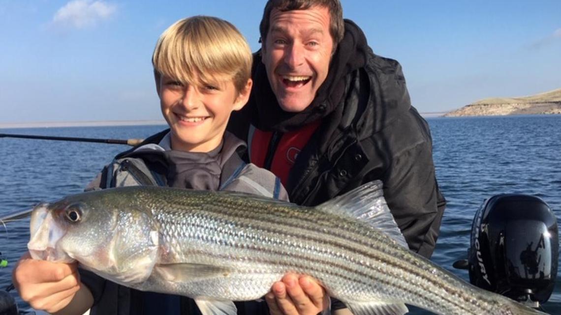 Nolan Chase, 12, of Oakdale (with his dad, Joel Chase) holds his personal-best 24-inch striper caught Dec. 12 on a trip with guide Roger George at San Luis Reservoir.