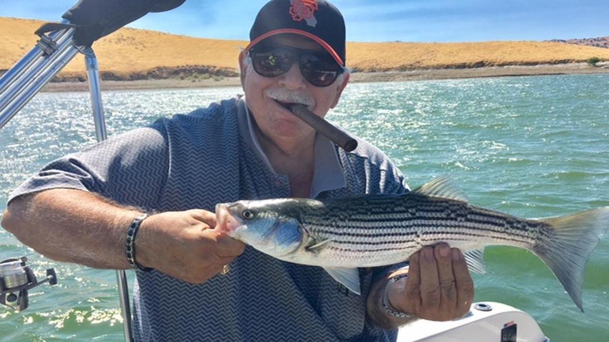 Marion Santos of Los Banos displays a nice schoolie striper he caught on the big lake at San Luis Reservoir.