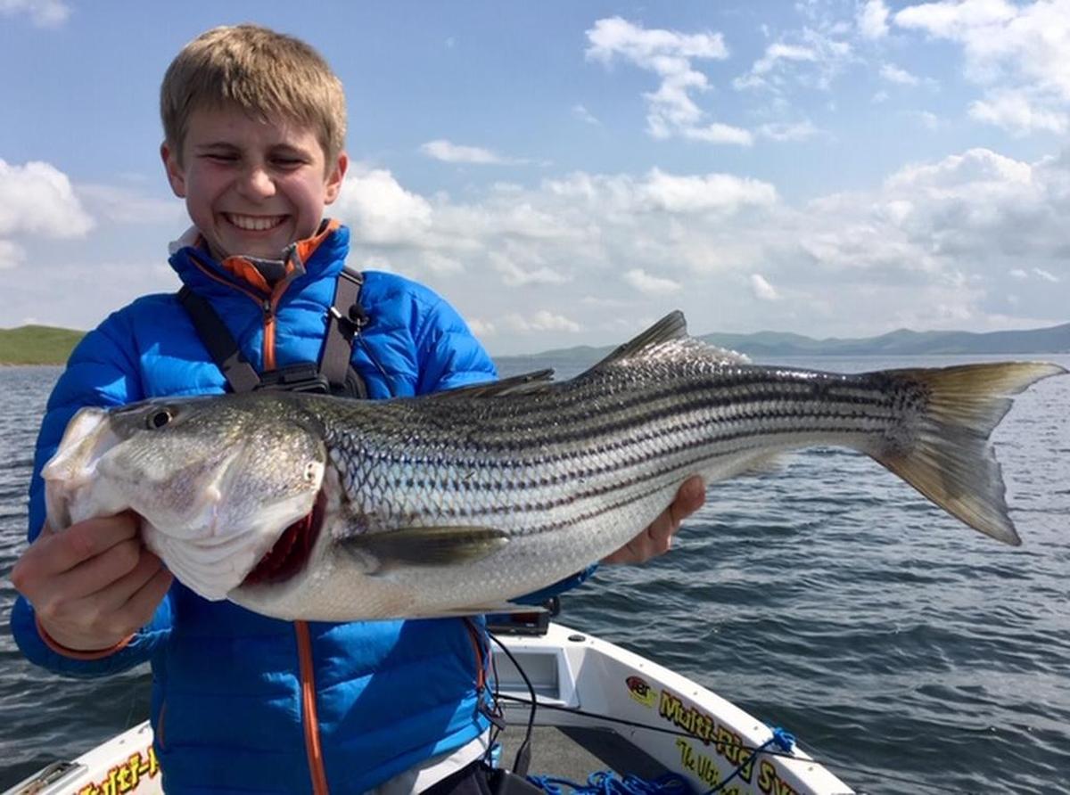 Logan Dieck shows off his personal-best 8.5-pound striper caught Saturday at San Luis Reservoir on a trip with his father, Martin, and guide Roger George.