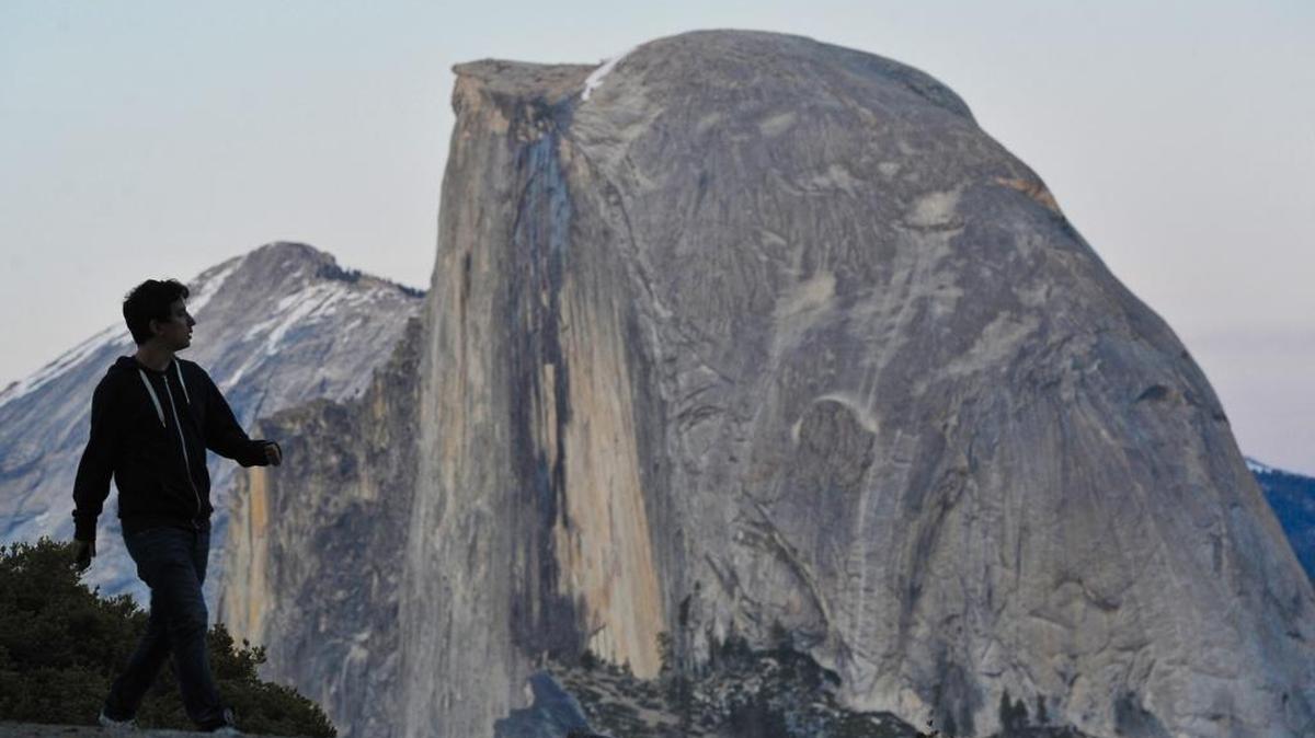 A tourist walks a trail at Glacier Point with the towering Half Dome in the background. Officials at Yosemite National Park are expecting large crowds for the Memorial Day weekend, and are asking visitors to plan accordingly.