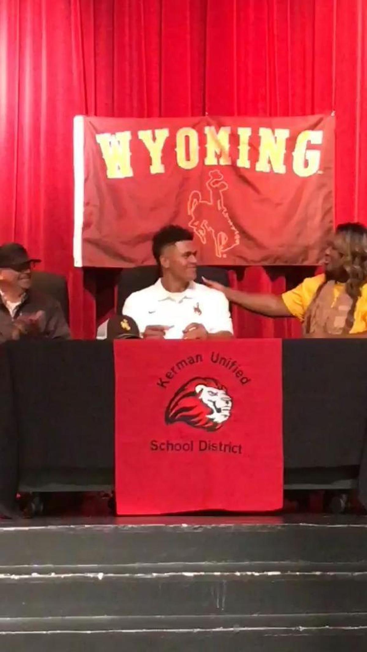 Sean Chambers is flanked by his parents during a signing ceremony Wednesday. The Kerman High quarterback signed with Wyoming.