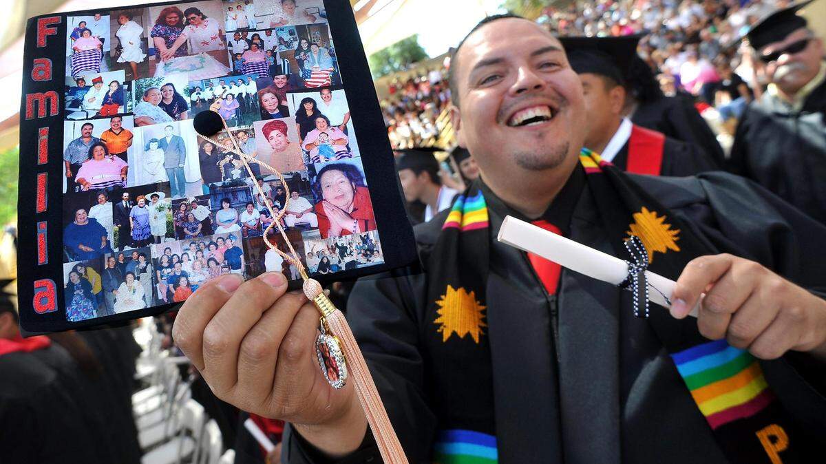 JOHN WALKER/THE FRESNO BEE Viendo a su familia entre la multitud, Raoul Hernández muestra alegremente su diploma y birrete, decorado con un collage de fotos familiares, en honor a su difunta abuela Benina Hernández, durante las ceremonias de graduación del Departamento de Educación de Trabajo Social de Fresno State, en el anfiteatro Rotary de Woodward Park, el viernes 18 de mayo de 2012 por la mañana. Galería en: www.fresnobee.com/picturethis