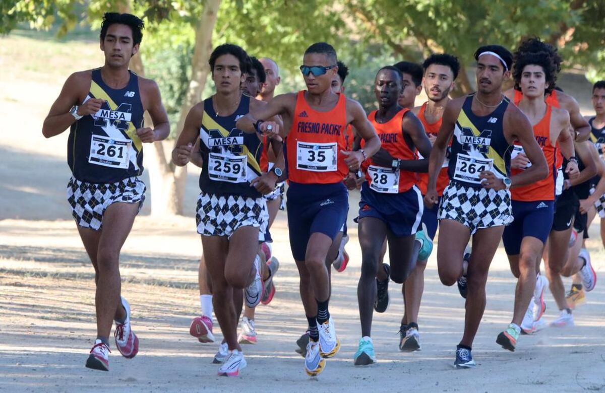 Fresno Pacific senior Xavier Smith – who won the 4-mile race (20:15.45) at the Sept. 3, 2022 Seawolf Invitational at Woodward Park – checks his watch as the lead pack approaches the 1-mile mark..