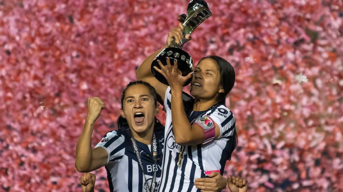 Desire Monsivais y Rebeca Bernal de Rayadas de Monterrey posan con el trofeo de campeonas luego de vencer a Tigres en la final del Torneo de Apertura de la Liga Femenil MX.