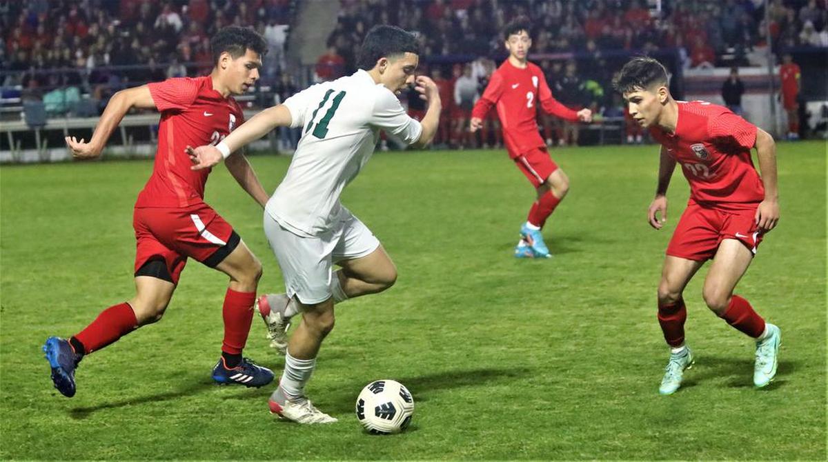 Reedley High senior Levy Alcántar tries to split two Sanger High defenders.