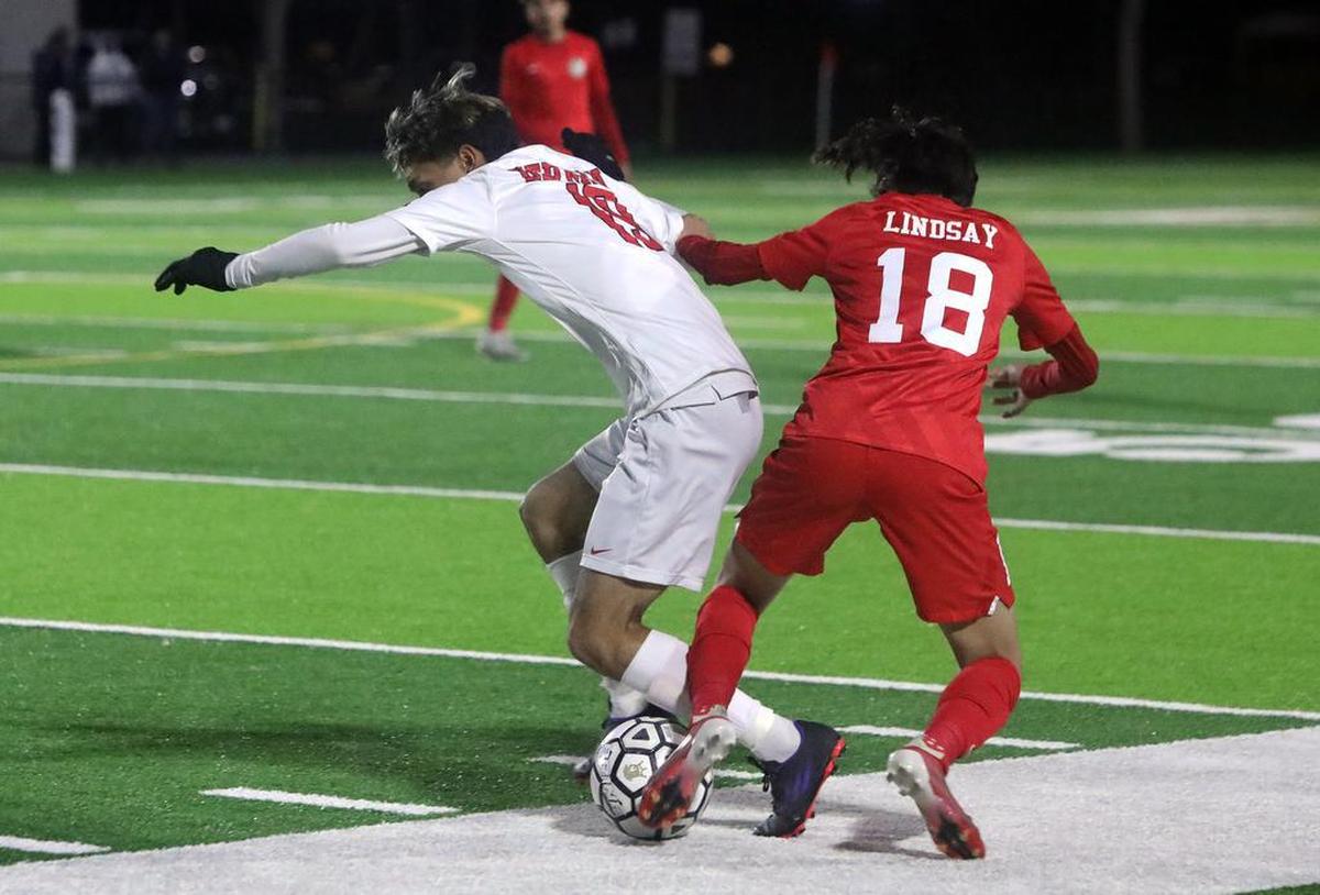 Alexis Espinoza of Kerman High tangles with a Lindsay High defender near the sidelines.