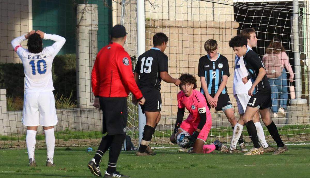 Clovis North senior goalkeeper Lucas Tabangcura stops a shot taken by Clovis High senior Kobe Iracheta during a TRAC match at Clovis Community College on Jan. 18, 2023. The Broncos improved to 14-0-1 with the 2-1 victory.