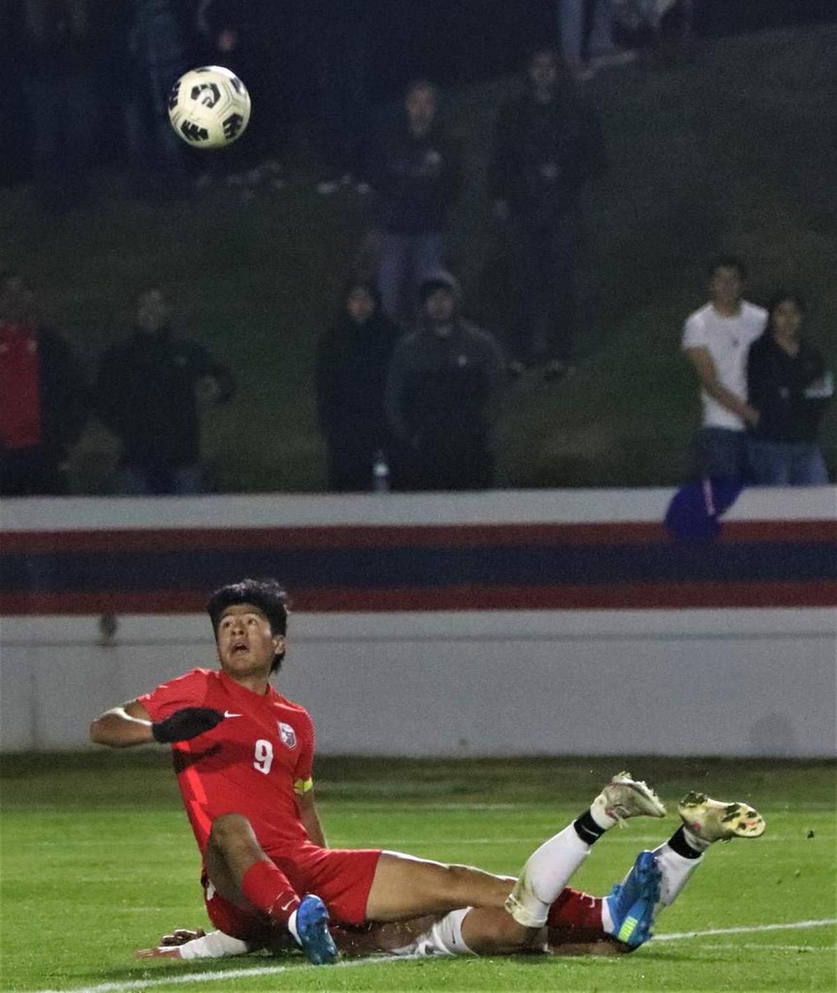 Isaiah Villalobos of Sanger High looks up at the ball after getting tripped by a Reedley defender.