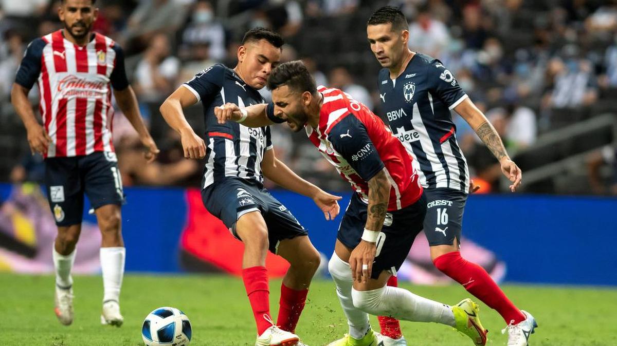 Carlos Rodríguez (i) de Rayados de Monterrey disputa el balón con Alexis Vega (c) de Chivas de Guadalajara el 21 de agosto durante un partido correspondiente al Torneo apertura 2021 celebrado en el estadio BBVA de la ciudad de Monterrey.