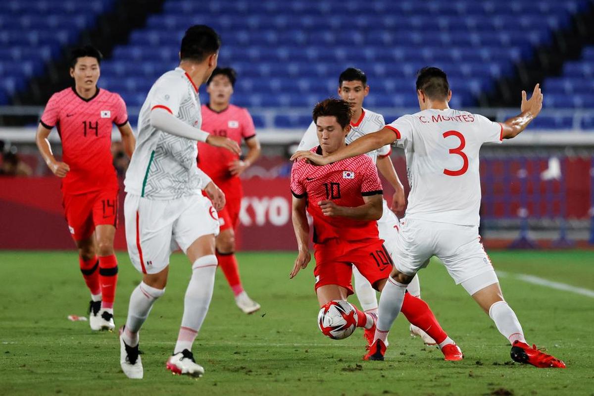 El defensa mexicano César Montes lucha por el balón con el centrocampista surcoreano Donggyeong en el encuentro de cuartos de final entre las selecciones de Corea del Sur y México, durante los Juegos Olímpicos 2020.