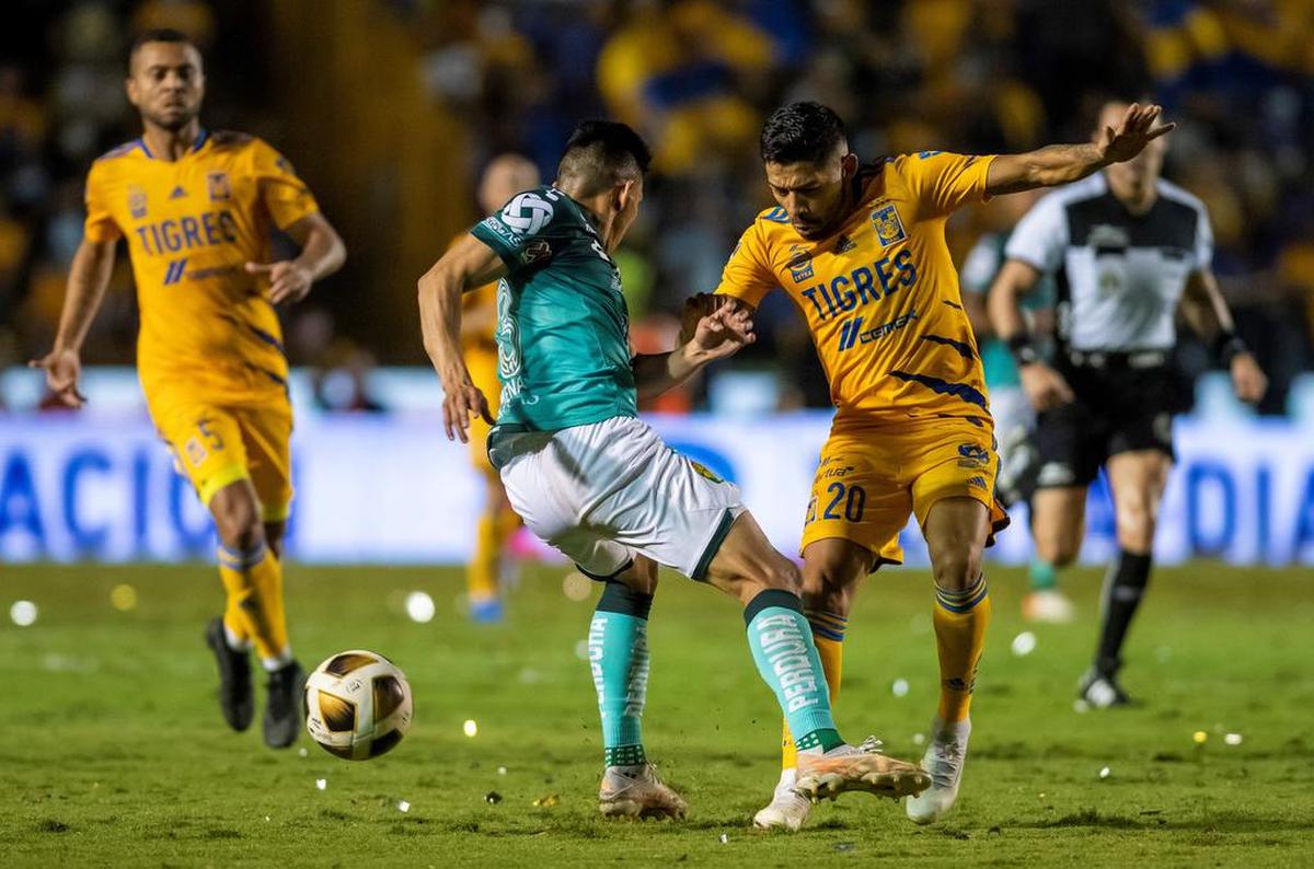 Javier Aquino (d) de Tigres disputa el balón con Ángel Mena del Club León, durante el partido de ida de las semifinales del Torneo Apertura 2021, en el estadio Universitario de Monterrey.