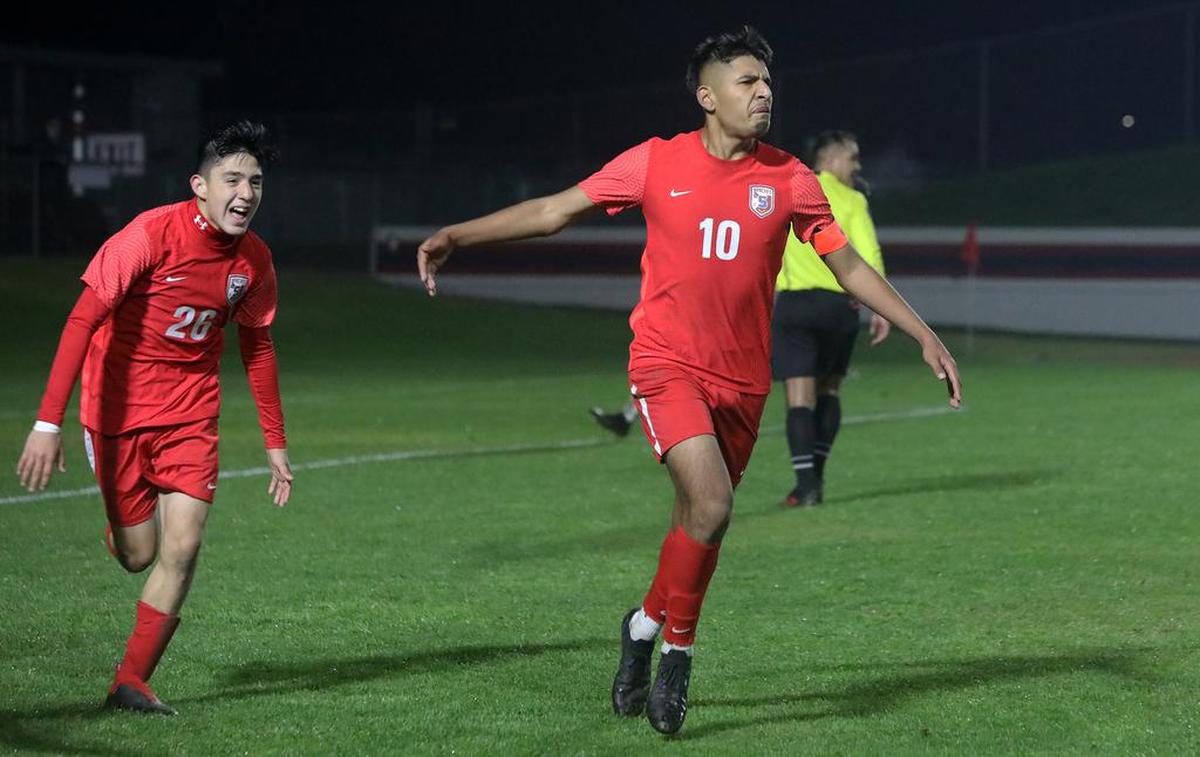 Sanger High midfielder Julio Hernández converted a penalty kick in the final minute of overtime to give the Apaches a 4-3 win over No. 1-ranked Clovis East on Dec. 10, 2021 at Tom Flores Stadium. Sanger was ranked No. 2 in the state. Teammate Santana Mercado celebrates behind Hernández.