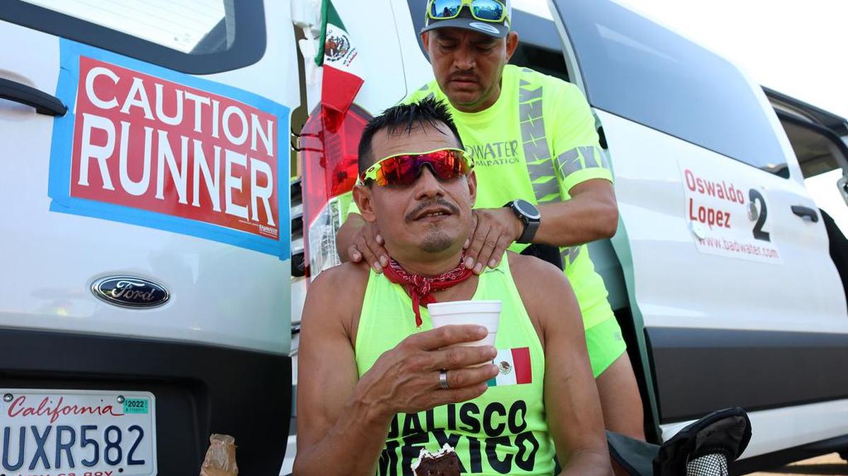 Oswaldo López of Madera munches on an ice cream as he gets a massage from crew member Enrique Rodríguez during a stop in Stovepipe Wells on July 20, 2021. The 49-year-old Hazmat worker and mariachi performer got his ninth finish in a 10th-place time of 31 hours, 46 minutes, 4 seconds.