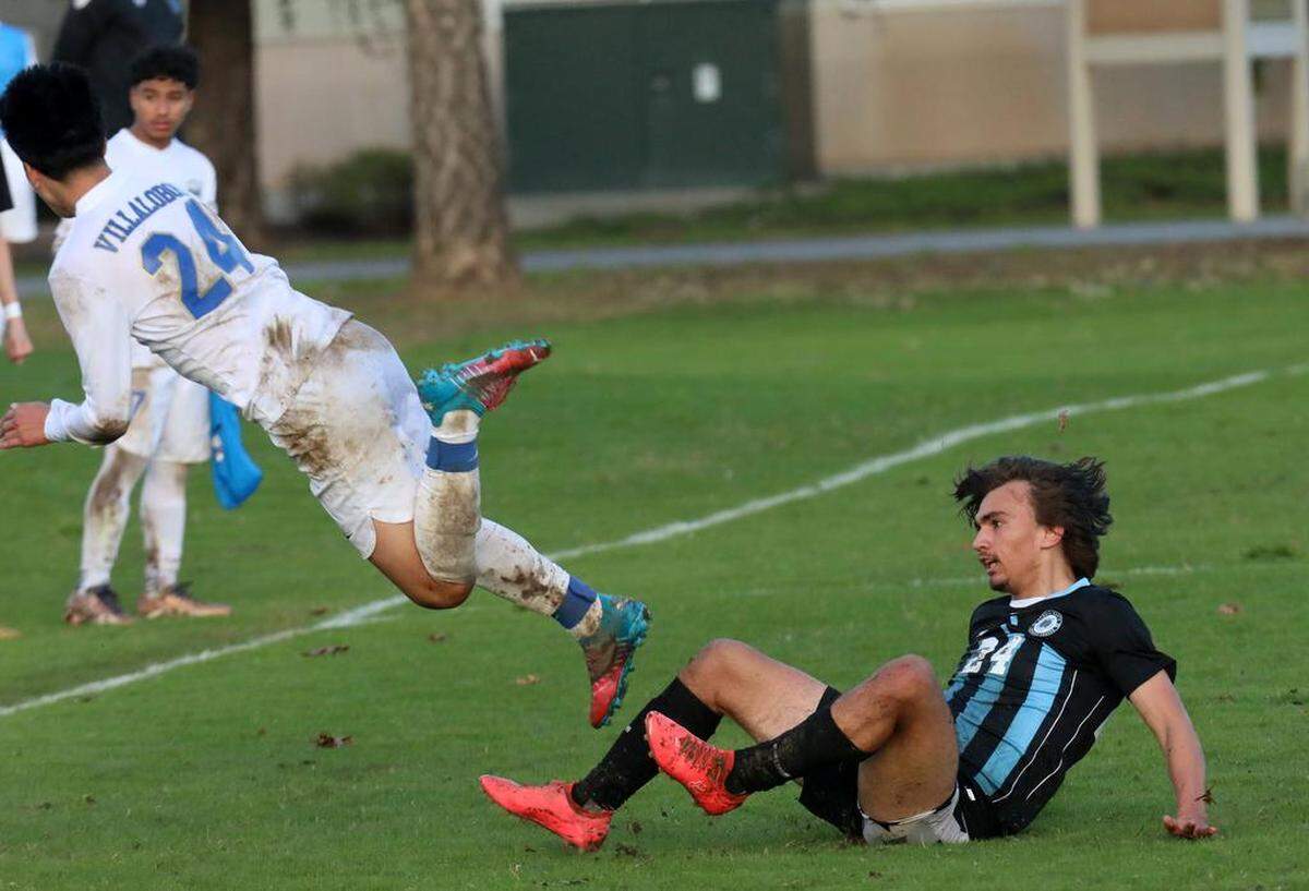 Clovis High senior Lorenzo Aguayo gets tripped by Clovis North senior forward Rocco Herzog during a TRAC soccer match at Clovis Community College on Jan. 18, 2023. The state’s top-ranked boys team, Clovis North, scored a 2-1 win.