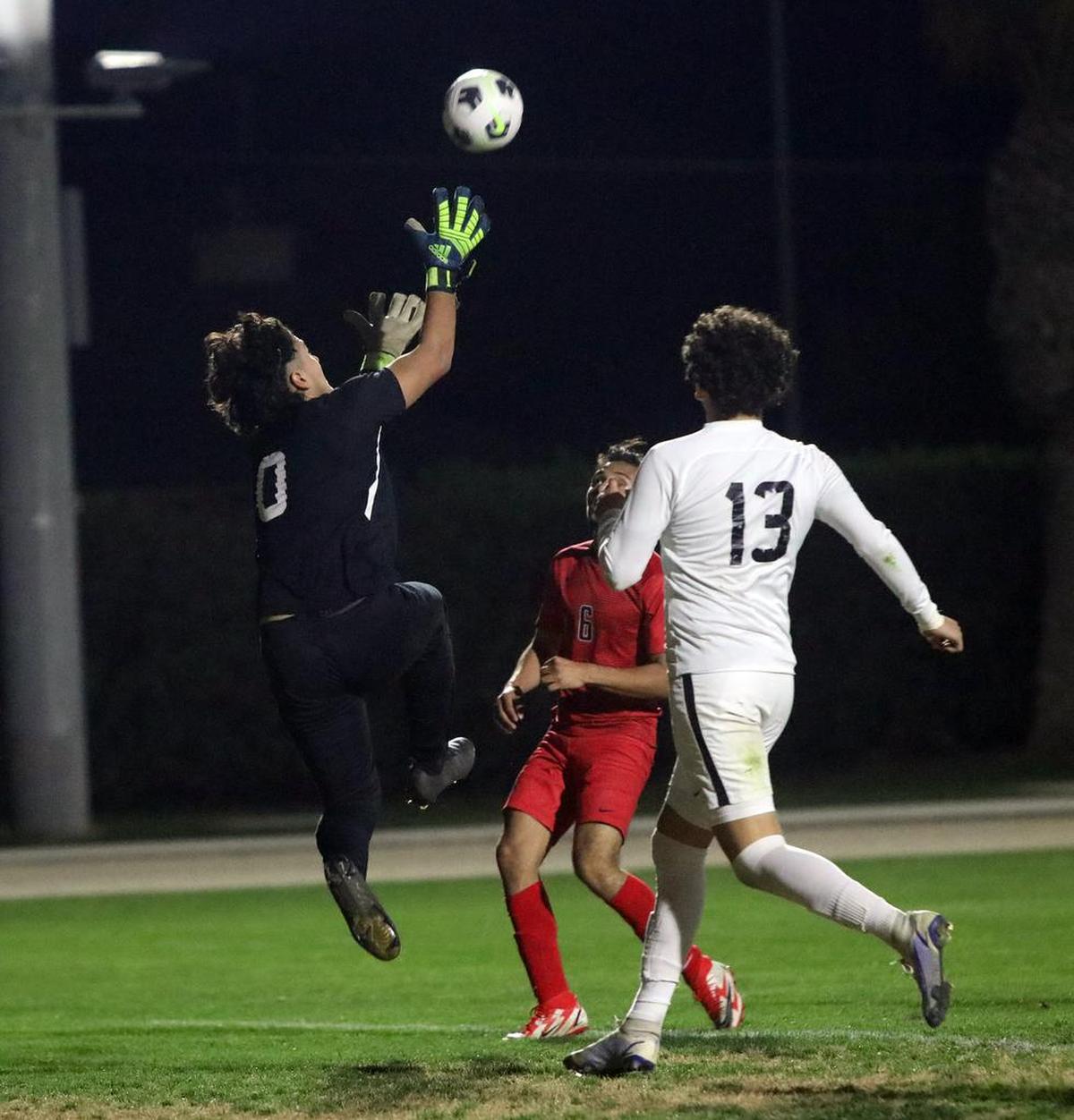 Madera High goalkeepr Chris Arias leaps to grab a shot during the first half against Kerman High on Feb. 16, 2022.