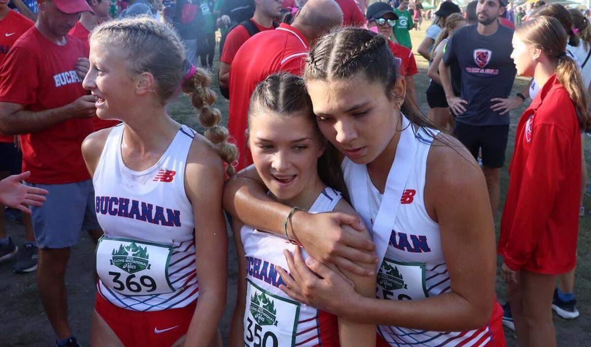 Buchanan High sophomore Elliana Lomelí hugs freshman teammate Kynzlee Buckley after the finish of the girls championship race of the 43rd Asics Clovis Invitational at Woodward Park on Oct. 8, 2022. On the left is freshman Taylor Torosian.