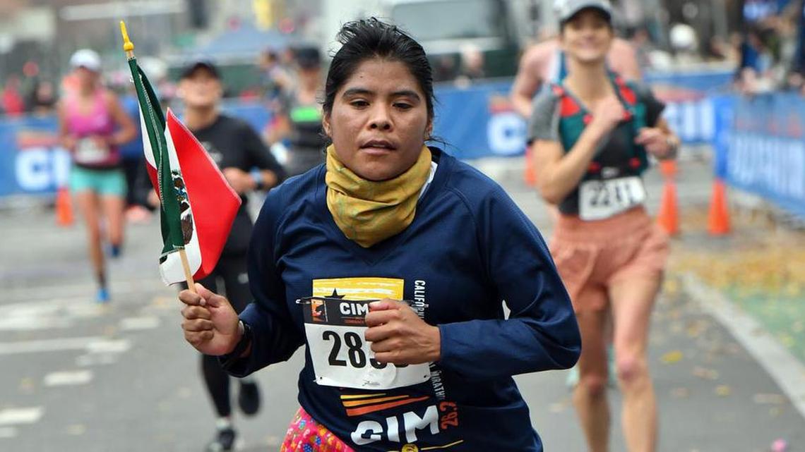 Rarámuri runner Lorena Ramírez holds a Mexican flag in her hand as she approaches the finish of the Dec. 5, 2021 California International Marathon.