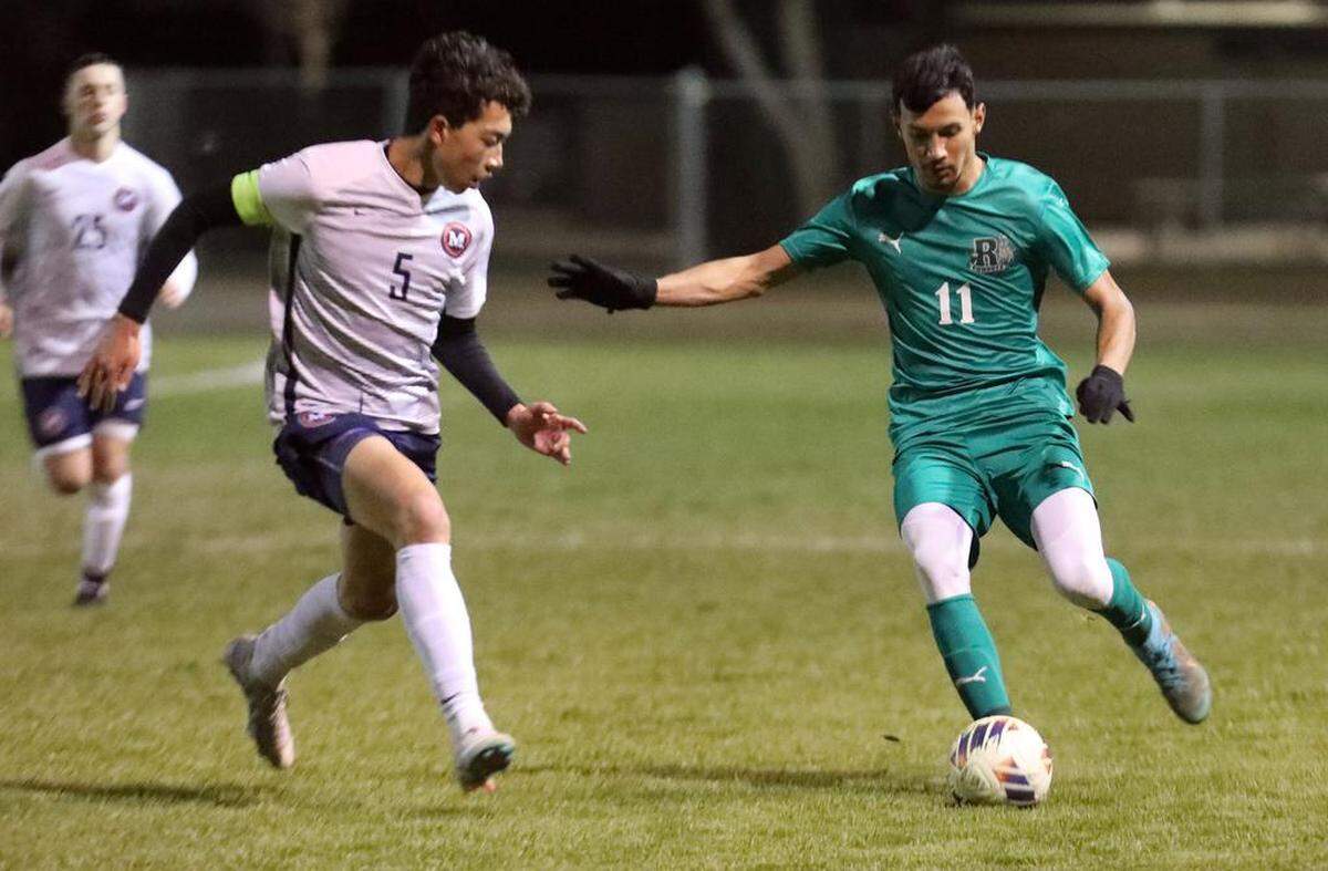 Riverdale High senior Isaac Romero looks to pass against San Joaquín Memorial defender Alex Bryan during a CIF Central Section Division IV boys soccer playoff match at Riverdale. The top-seeded Riverdale Cowboys advanced with a 1-0 win to improve to 18-4-4.
