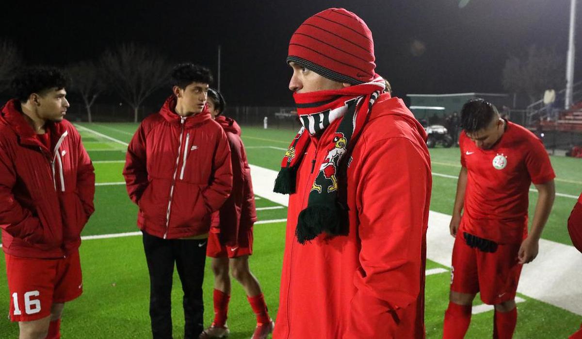 Lindsay High School boys soccer coach Tony Godoy tries to keep warm following his team's 3-1 win over Farmersville High.