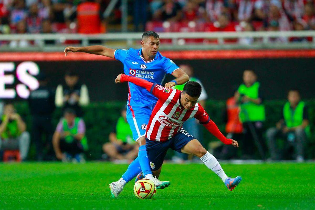 Fernando Beltrán (d) del Guadalajara disputa el balón con Julio Domínguez (i) de Cruz Azul este 22 de abril de 2023, durante un partido entre Guadalajara y Cruz Azul.