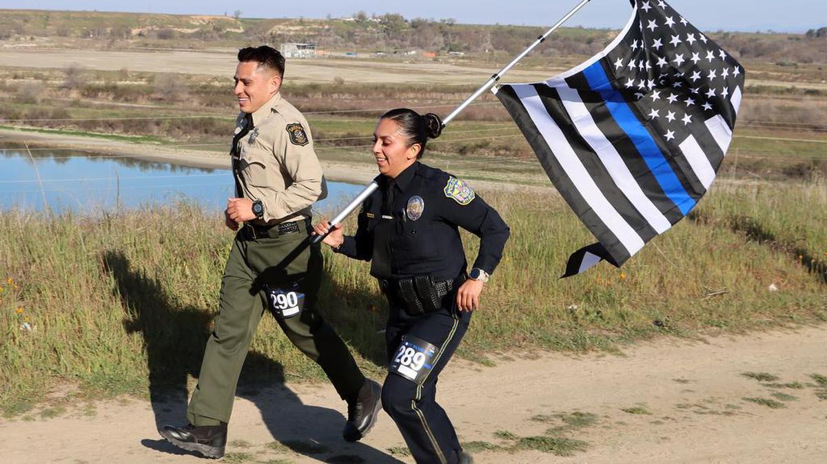 A Stanislaus County Sheriff’s officer and a Turlock Police officer run with a U.S. flag during the Support the Blue Half Marathon on Feb. 26, 2022 on a course through Woodward Park.