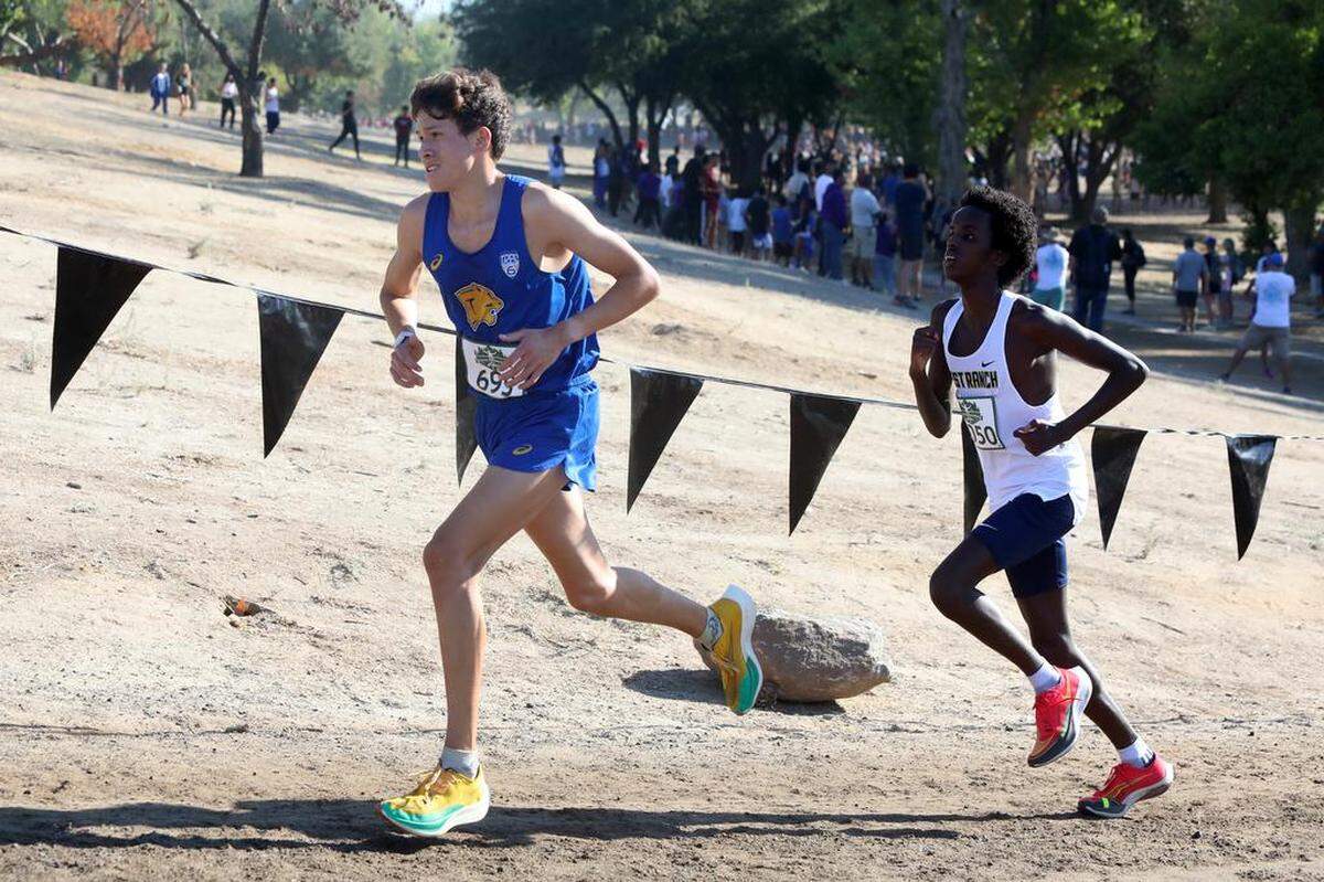 Clovis High senior Christopher Caudillo makes up a hill ahead of Bille Issa of West Ranch during the boys championship race of the 43rd Asics Clovis Invitational at Woodward Park on Oct. 8, 2022. Caudillo finished fourth in 15:03.9.