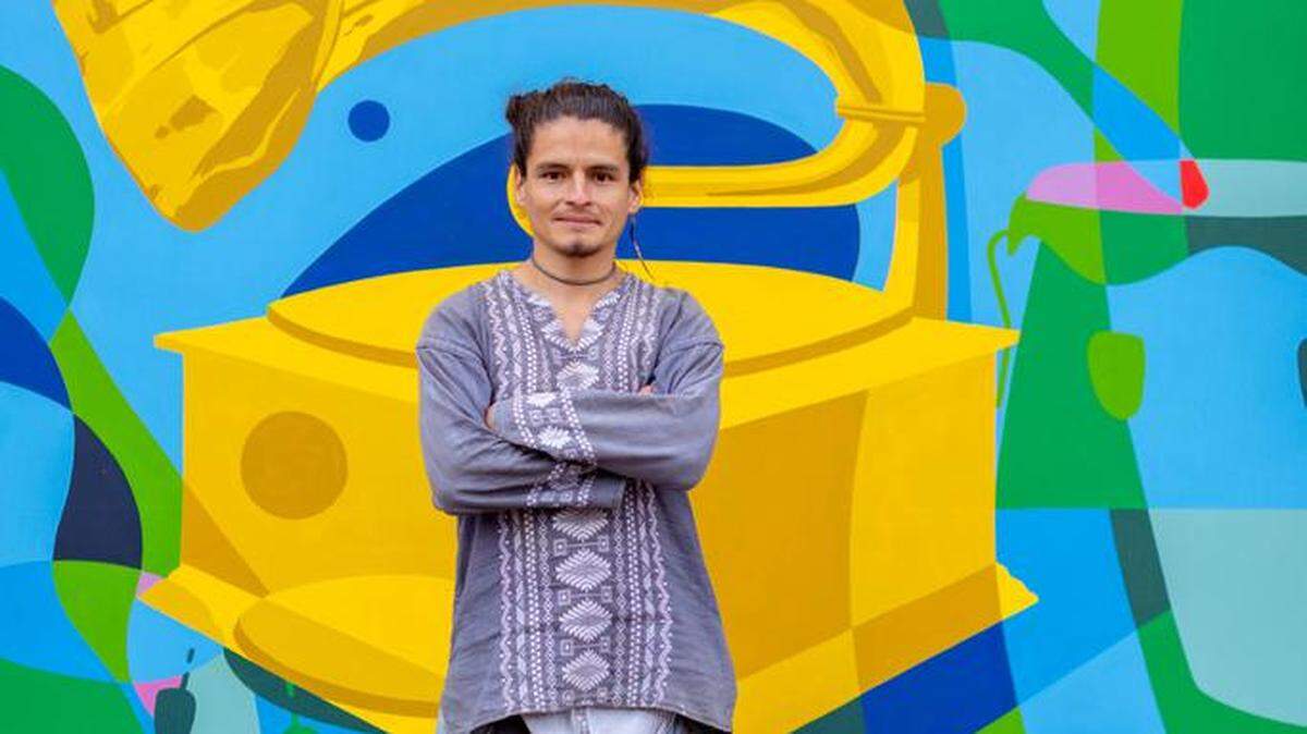 Fotografía cedida por la Academia Latina de la Grabación donde aparece el muralista mexicano Quetzal Fuerte mientras posa junto al mural con el gramófono, que es el símbolo de la Academia, y otros instrumentos musicales, pintado en Morelia.