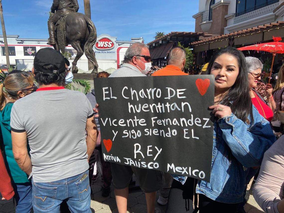 Una mujer sostiene una pancarta de homenaje a Vicente Fernández (1940-2021), durante la inauguración de una estatua de 3.7 metros de altura del que fuera conocido como el “rey de la canción mexicana”, en el centro de ocio Plaza La Alameda, a las puertas de un restaurante con el nombre del artista, en Huntington Park.