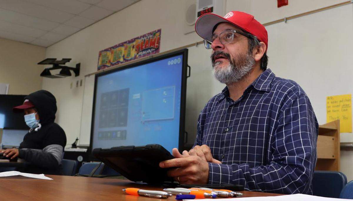 Román Pinal, statewide organizing director for the United Farm Workers, helps a family apply for a $600 debit card from the U.S. Department of Agriculture for pandemic relief. The event took place March 26, 2023 at César E. Chávez Middle School.