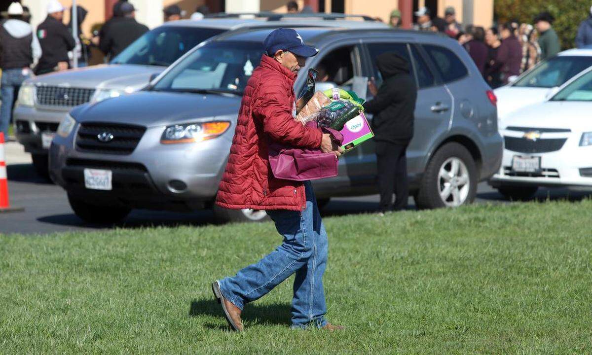 A man carries a box of food during the distribution of food to about 400 families who were impacted by flooding in Planada. The distribution by the United Farm Worker took place at César E. Chávez Middle School on March 26, 2023.